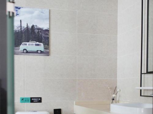 a bathroom with a sink and a van on the wall at Xana Hotelle·Heze Railyway Station in Zhaolou