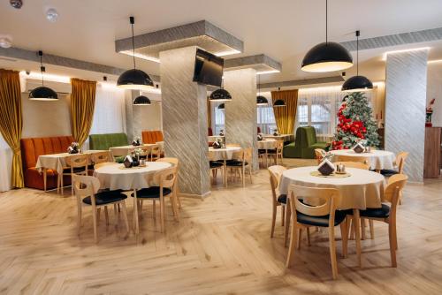 バコヴェルにあるHOTEL & SPA Zatyshnyi Dvirのテーブルと椅子、クリスマスツリーのあるレストラン