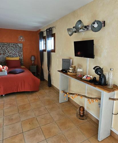 a bedroom with a bed and a desk with a television at Chambre d'hôtes et de charme "Au Clos des Ammonites chez Ange&Sébastien " in Labeaume