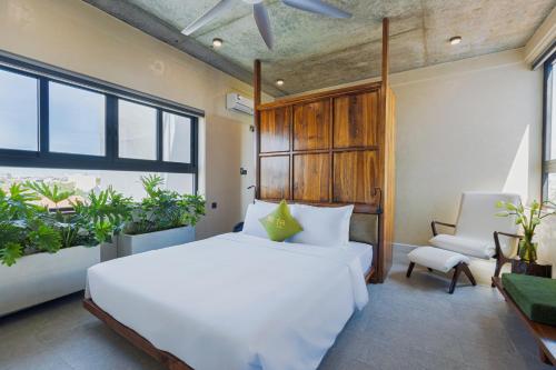 a bedroom with a large white bed and a chair at TA Hue Boutique Hotel in Hue