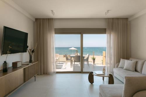 a living room with a couch and a view of the ocean at Costel BeachFront Residence, BBQ & Private Sunbeds, By ThinkVilla in Fodele