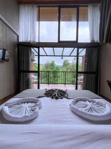 a bedroom with a bed with white sheets and a window at Ella Tea Heaven Resort in Ella