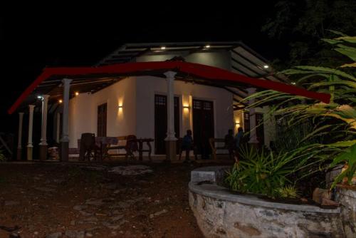 una casa con una sombrilla roja delante por la noche en Ecovert Residence Sinharaja, en Kalawana
