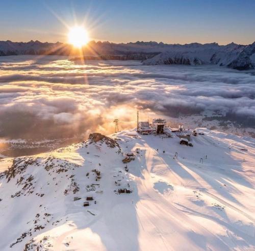a view of a snow covered mountain with the sun above the clouds at Exklusive Ferienwohnung Im Hotel Mit Wellness in Laax