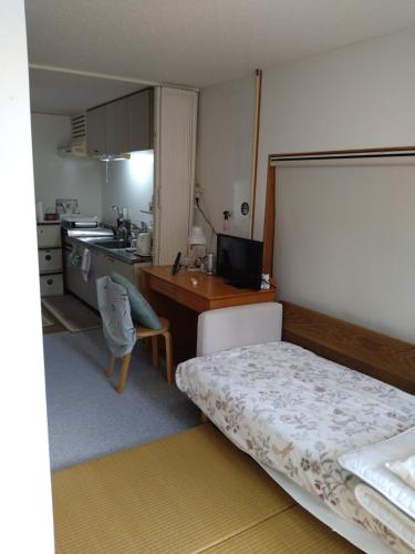 a bedroom with a bed and a desk and a kitchen at Minshuku Zabaru in Ishigaki Island