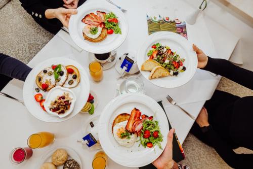 personas sentadas en una mesa con platos de comida en Hotel Buczyński Medical & SPA, en Świeradów-Zdrój