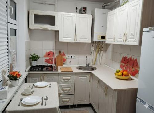 eine weiße Küche mit weißen Schränken und einer Spüle in der Unterkunft Уютная 1 комнатная квартира в самом центре Шымкента in Zhezdi