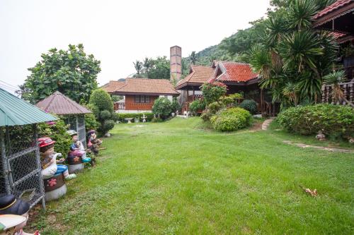 a yard of a house with children sitting on the lawn at Tanyaporn House in Haad Rin