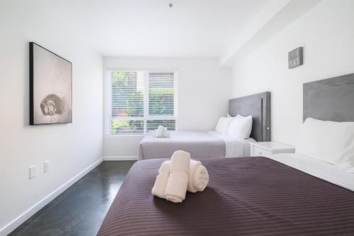 a white bedroom with two beds and a window at The Heart Of Hollywood Hills in Los Angeles