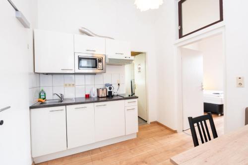 a kitchen with white cabinets and a wooden table at 110 Messe Apartment Casablanca 2-4 Pers 42 m2 in Klagenfurt