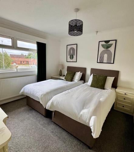 a bedroom with two beds and a window at Spacious House Parking Pool Table in Balderton