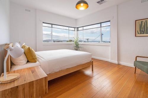 a white bedroom with a large bed and a window at 1950 Serenity - Classic Hobart Escape near CBD in West Hobart