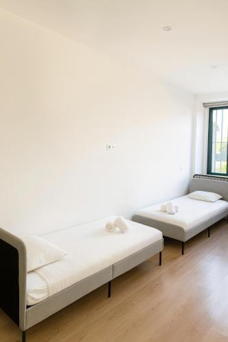 two beds in a room with white walls and wooden floors at Douro Vila 10 - Best View in Town in Bandeira