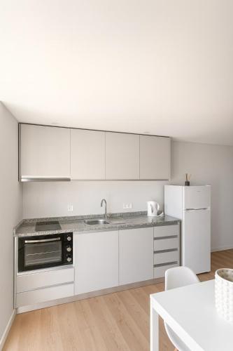 a kitchen with white cabinets and a sink and a refrigerator at Douro Vila 10 - Best View in Town in Bandeira