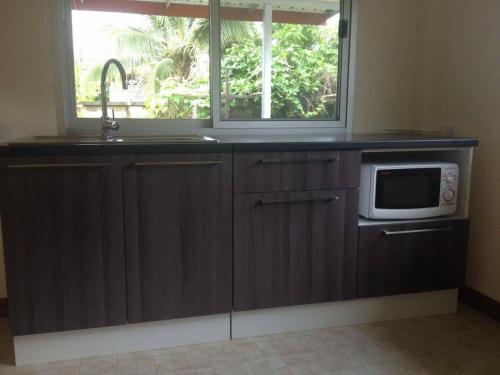 a kitchen with a microwave and a sink and a window at JS HOUSE Singha Park Chiang Rai in Ban Mae Kon