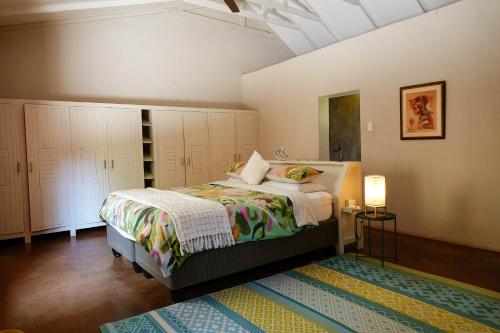 a bedroom with a bed with white cabinets and a rug at Hluhluwe Homestead in Hluhluwe