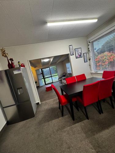 a kitchen with a table and red chairs and a refrigerator at Relax In Mosgiel in Mosgiel