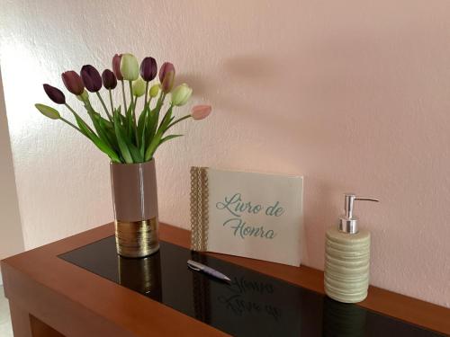a vase of flowers on a table with a sign at Casa das Cales - Grande in Altares