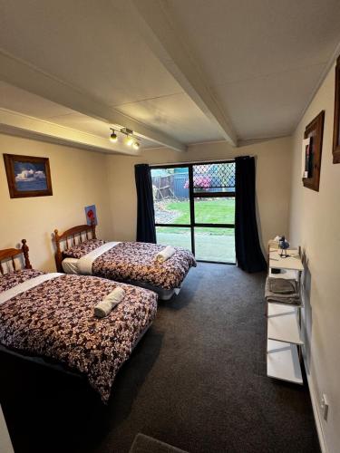 a bedroom with two beds and a large window at Relax In Mosgiel in Mosgiel