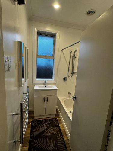 a bathroom with a tub and a sink and a shower at Relax In Mosgiel in Mosgiel