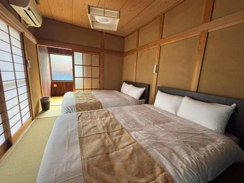 a bedroom with two beds and two windows at P-Stay宮島中西町 in Hatsukaichi
