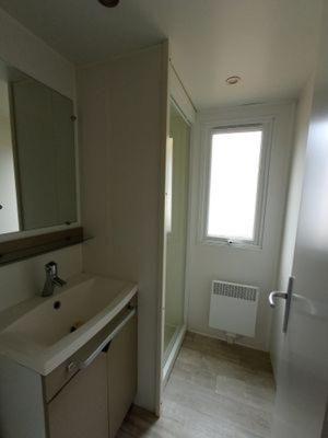 a white bathroom with a sink and a window at Les mobilhomes du vélodrome in Albert