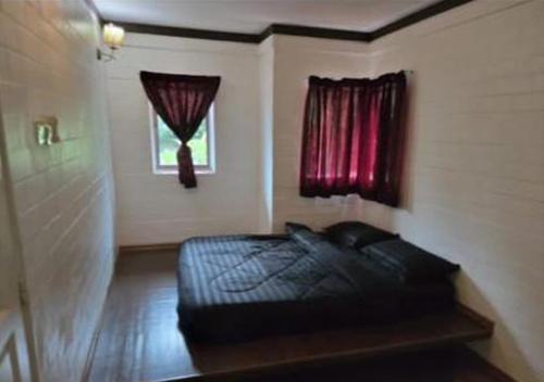 a bedroom with a black bed and a window at Villa Ilham in Langkawi Intl