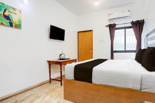 a bedroom with a bed and a desk and a television at Collection O Candolim Beach Formerly Poornima Place in Candolim
