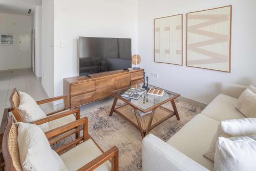 a living room with a tv and a table at Frank Porter - Parkside 2, Emaar South in Ghantoot