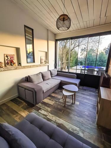 a living room with a couch and a table at L'échappée, piscine, billard et parking privé in Lagord