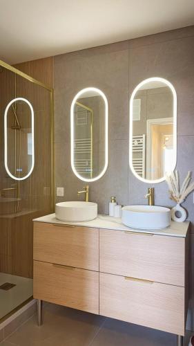une salle de bains avec deux lavabos et deux miroirs dans l'établissement Escapade Rochelaise, à La Rochelle