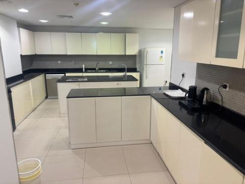 a kitchen with white cabinets and black counter tops at Elegant apartment overlooking the sea in Jeddah
