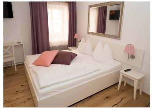 
a white bed sitting in a bedroom next to a window at Madar Café Restaurant zum Fürsten in Melk
