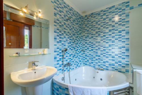 a blue tiled bathroom with a tub and a sink at Motel Venecia in Taboadela