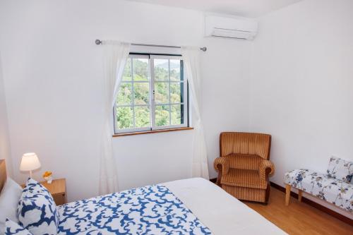 a bedroom with a bed and a window and a chair at Casa Belavista no Geres by In'Canto Property Management in Ponte da Barca