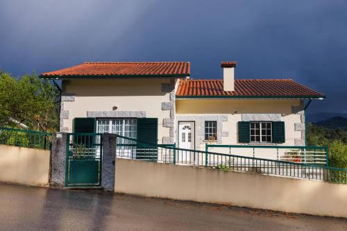 a white house with green doors and a fence at Casa Belavista no Geres by In'Canto Property Management in Ponte da Barca
