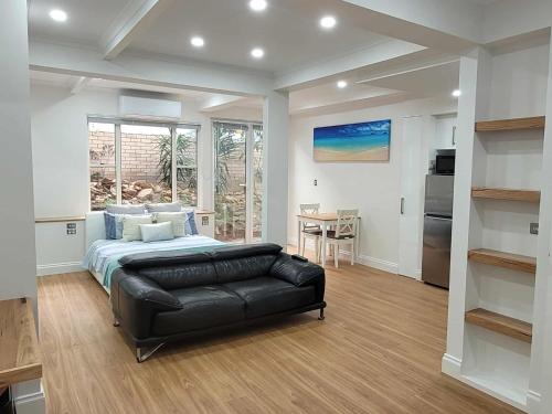 a bedroom with a bed and a leather couch at Luxury Resort Studio Apartment Retreat with Pool, Tennis & Alfresco 