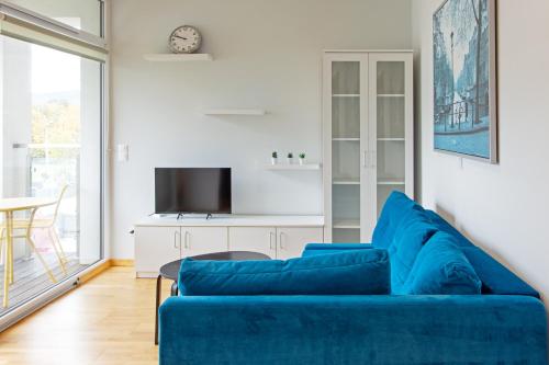 ein Wohnzimmer mit einem blauen Sofa und einem Tisch in der Unterkunft Szyndzielnia Park no 26 # kortem tenisowym, rowerownią # Nestapartamenty in Bielsko-Biała