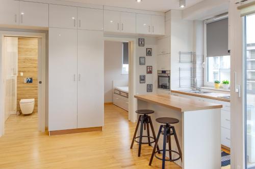 eine Küche mit weißen Schränken und Barhockern in der Unterkunft Szyndzielnia Park no 26 # kortem tenisowym, rowerownią # Nestapartamenty in Bielsko-Biała