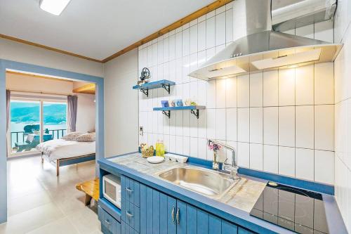 a kitchen with a sink and a room with a bed at Sinbibada pension in Geoje 