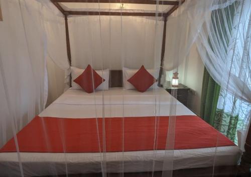 ein Schlafzimmer mit einem Himmelbett mit roten und weißen Kissen in der Unterkunft Serenità Moon Villa in Tangalle