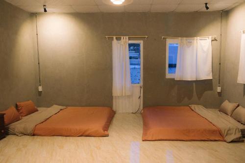 two beds in a room with a window at Brownie Home Dalat in Da Lat