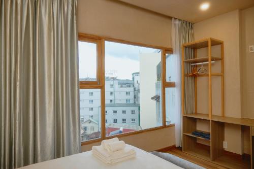 Un dormitorio con una cama y una ventana grande en Enjoy Hotel Đà Lạt, en Da Lat