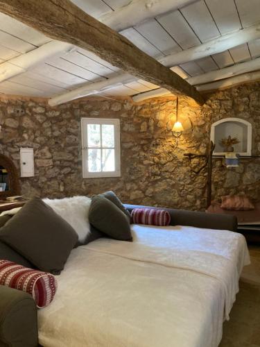 a large bed in a room with a stone wall at Terre de Caliso in Carnoules