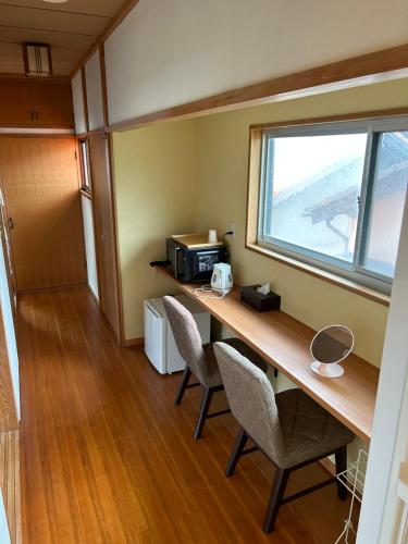 Una habitación con un escritorio con sillas y una ventana. en 白浜の宿梅 別館, en Shirahama