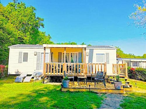 a mobile home with a deck and chairs in a yard at Les Ch'tis Normands 2! in Litteau
