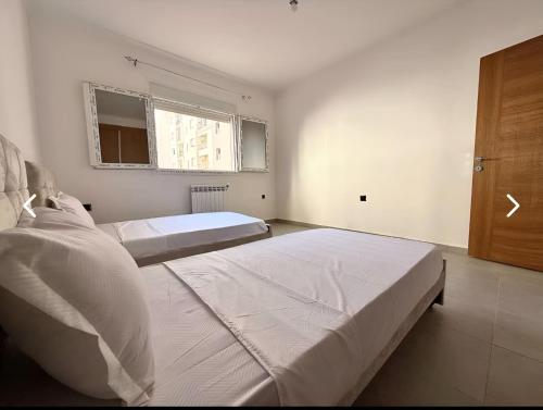 a bedroom with two beds and a wooden door at Charming apartment in Oran in Bir el Djir