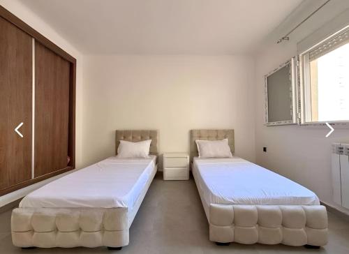 two beds in a room with white walls at Charming apartment in Oran in Bir el Djir