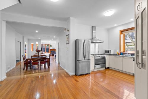 a kitchen and dining room with a table and a refrigerator at Large 5BR Home-Pool-BBQ-5 CarPark-Central Location in Melbourne