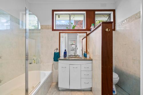 a bathroom with a tub and a sink and a toilet at Large 5BR Home-Pool-BBQ-4 CarPark-Central Location in Melbourne